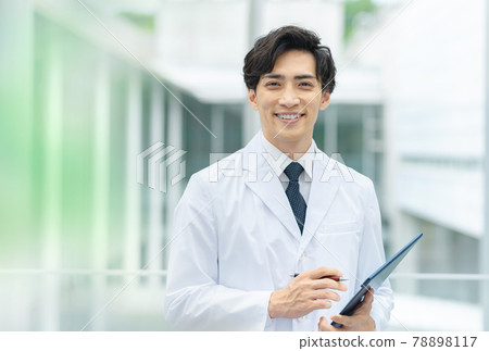 A young doctor in a white coat looking at a medical record at the hospital 78898117