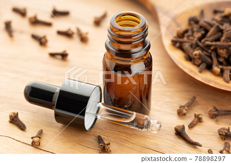 Clove essential oil on bottle on wooden table. Alternative medicine 78898297