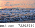 Waves approaching the sea and beach illuminated by the setting sun 78898539
