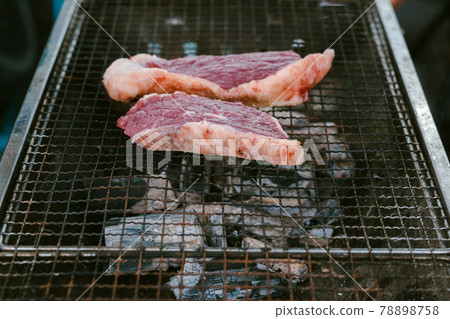 Grill the beef on the charcoal grill to cook steaks. 78898758