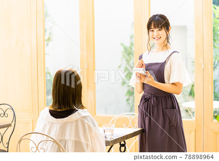 Young female clerk listening to an order at a cafe 78898964