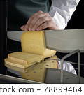 Unknown person cuts cheese using a cheese slicer 78899464