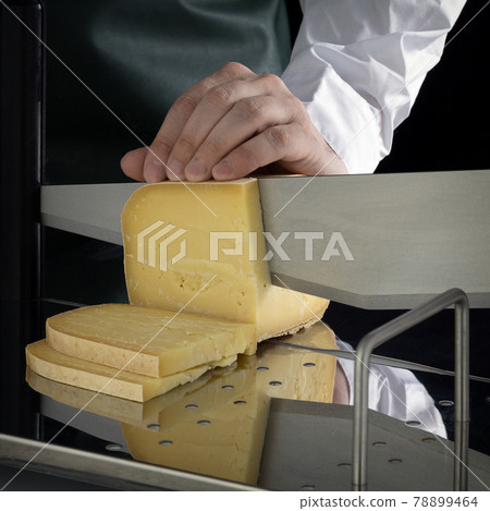 Unknown person cuts cheese using a cheese slicer 78899464