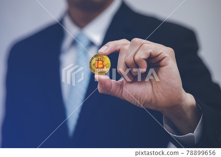 Businessman Hand holding Bitcoin New virtual money coin over us dollars close up, Digital Money and Bitcoin Concept. Cryptocurrency golden coin, stock exchange graph background. Digital money concept. Businessman Hand holding Bitcoin New virtual money coin over us dollars close up, Digital Money and Bitcoin Concept. Cryptocurrency golden coin, stock exchange graph background. Digital money concept. 78899656