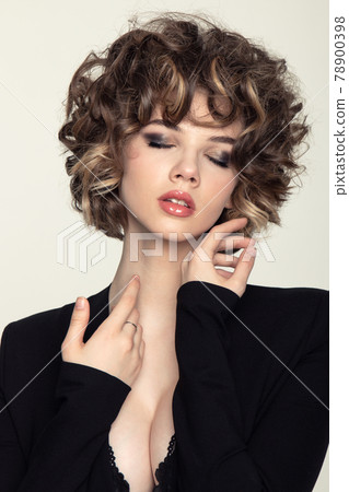 Beautiful european girl with curls with a fan in black dress on a white background 78900398