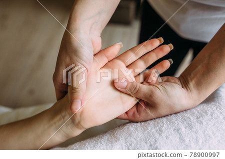 The masseur gives massage to female hand at the spa. 78900997