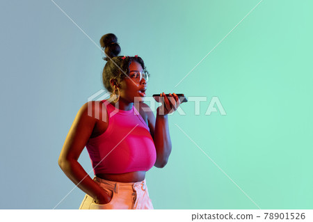 Young beautiful happy African girl isolated on blue-green background in neon. 78901526