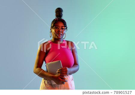 Young beautiful happy African girl isolated on blue-green background in neon. 78901527