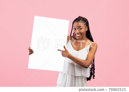 Smiling African American woman pointing at empty banner with space for your design on pink background 78903525