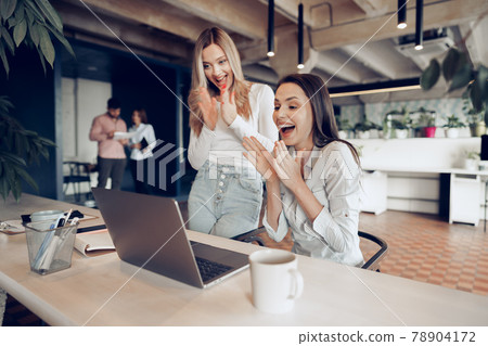 Two young happy businesswomen celebrating project success in office Two young happy businesswomen celebrating project success in office 78904172