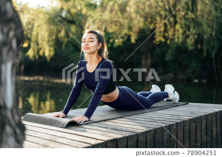 Fit young woman exercising on mat in the park Fit young woman exercising on mat in the park 78904251