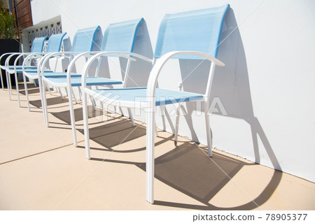 Outdoor lounge chairs. Blue patio chairs at sunny wall. Patio or poolside furniture for leisure 78905377