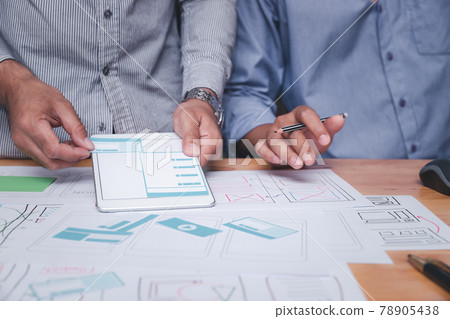 UX or UI designers designing on their smartphone application layout prototype project. UX or UI designers designing on their smartphone application layout prototype project. 78905438