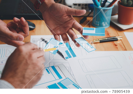 UX or UI designers designing on their smartphone application layout prototype project. 78905439