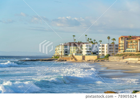 Buildings overlooking the ocean with waves crashing on the shore in San Diego CA 78905824