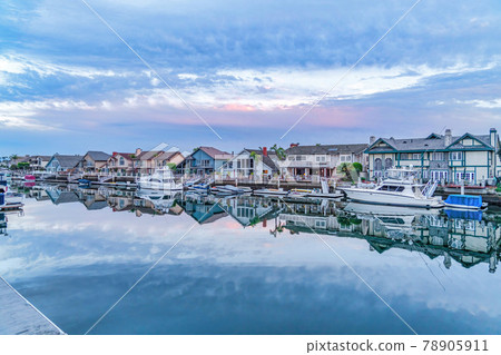 Boats and yachts on scenic harbor water that reflects the cloudy sky at sunset 78905911