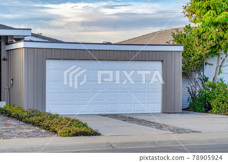 Exterior of home garage with white door and gray wall against sky at sunset Exterior of home garage with white door and gray wall against sky at sunset 78905924