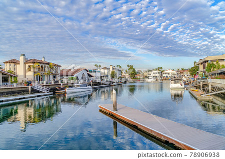 Boats and private docks on sea reflecting cloudy blue sky in Huntington Beach CA 78906938