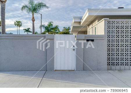 White gate and concrete fence agaonst trees and cloudy sky of beautiful home White gate and concrete fence agaonst trees and cloudy sky of beautiful home 78906945