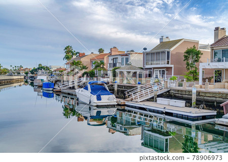 Houses with private docks bordering the canal with reflection of overcast sky 78906973