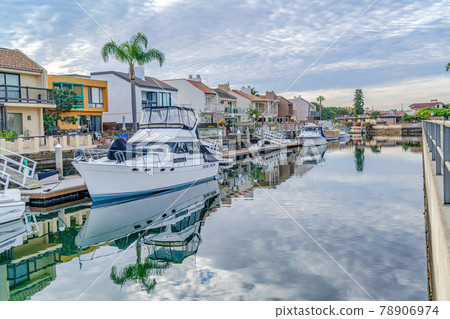 Overcast sky over houses overlooking scenic canal with boats and private docks 78906974