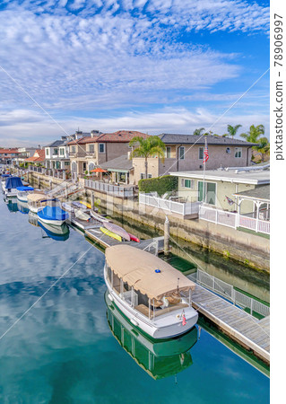 Boats and private docks of houses along canal that reflects cloudy blue sky Boats and private docks of houses along canal that reflects cloudy blue sky 78906997