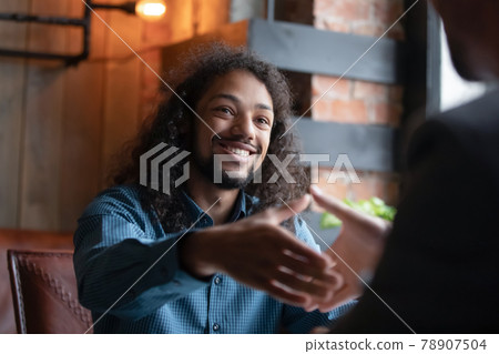 Happy young mixed race guy shaking hands with agent. Happy young mixed race guy shaking hands with agent. 78907504