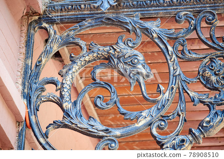 Balcony decoration element of an old house. Openwork forging in the shape of a fish with a protruding tongue. 78908510