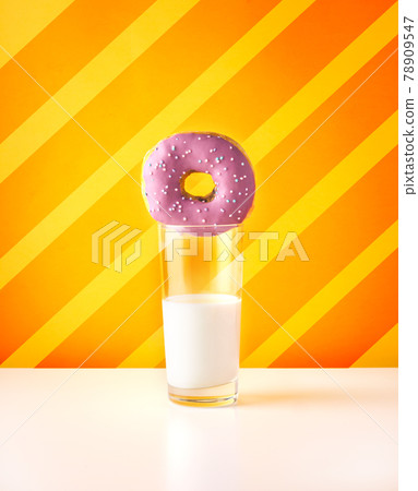 Purple doughnut with glass of milk on striped orange background Purple doughnut with glass of milk on striped orange background 78909547