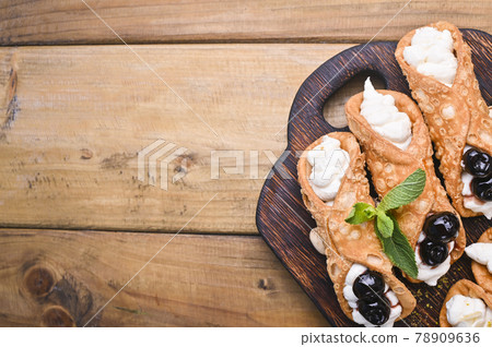 Cannoli Sicily. Traditional Italian sweet with ricotta and various fillings. Food on a wooden Cannoli Sicily. Traditional Italian sweet with ricotta and various fillings. Food on a wooden 78909636