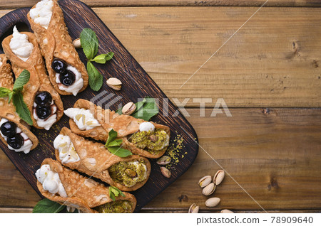 Cannoli Sicily. Traditional Italian sweet with ricotta and various fillings. Food on a wooden 78909640