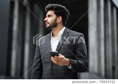 Arabian businessman standing on street and holding mobile 78910152