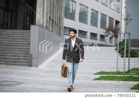 Muslim businessman with suitcase walking outdoors 78910211