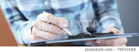 Manager sits at his desk and holds documents with pen 78910284