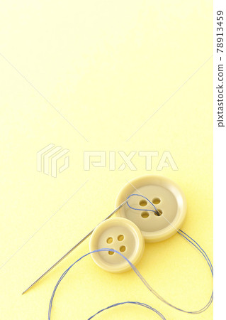 Shooting buttons, needles and threads on a light yellow background 78913459