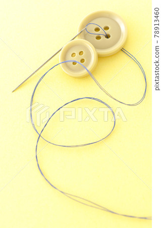 Shooting buttons, needles and threads on a light yellow background Shooting buttons, needles and threads on a light yellow background 78913460