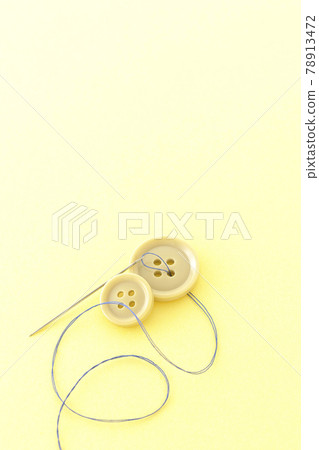 Shooting buttons, needles and threads on a light yellow background Shooting buttons, needles and threads on a light yellow background 78913472