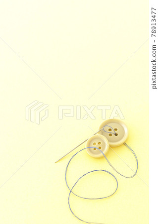 Shooting buttons, needles and threads on a light yellow background Shooting buttons, needles and threads on a light yellow background 78913477
