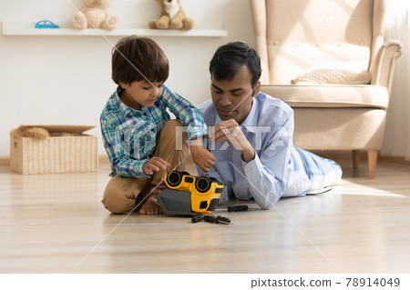 Indian father and small son repair toy car together Indian father and small son repair toy car together 78914049