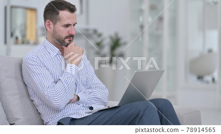 Pensive Young Man using Laptop at Home Pensive Young Man using Laptop at Home 78914565