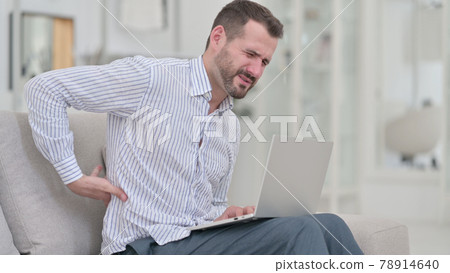 Young Man with Back Pain using Laptop at Home  78914640