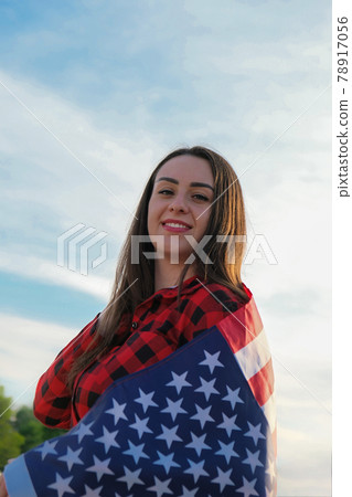 Young millennial brunette woman holding The National Flag of USA. American Flag. Tourist traveler or patriotism. Immigrant in free country. July 4th Independence Day. Caucasian Young millennial brunette woman holding The National Flag of USA. American Flag. Tourist traveler or patriotism. Immigrant in free country. July 4th Independence Day. Caucasian 78917056
