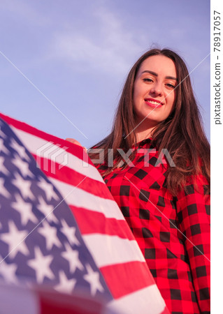 Young millennial brunette woman holding The National Flag of USA. American Flag. Tourist traveler or patriotism. Immigrant in free country. July 4th Independence Day. Caucasian Young millennial brunette woman holding The National Flag of USA. American Flag. Tourist traveler or patriotism. Immigrant in free country. July 4th Independence Day. Caucasian 78917057