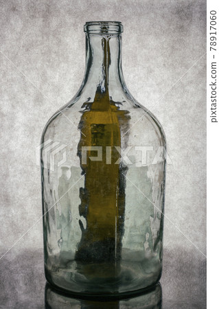 Still life with a transparent glass bottle on a gray background 78917060