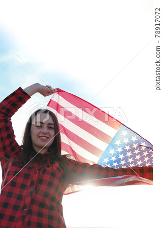 Young millennial brunette woman holding The National Flag of USA. American Flag. Tourist traveler or patriotism. Immigrant in free country. July 4th Independence Day. Caucasian Young millennial brunette woman holding The National Flag of USA. American Flag. Tourist traveler or patriotism. Immigrant in free country. July 4th Independence Day. Caucasian 78917072