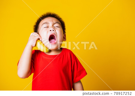 child or kid cute little boy attractive smile playing holds banana fruit pretending to be like a telephone child or kid cute little boy attractive smile playing holds banana fruit pretending to be like a telephone 78917252