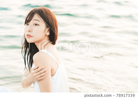 One-piece woman sitting on the beach 78917339