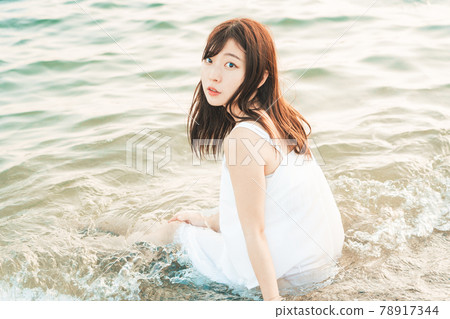 One-piece woman sitting on the beach 78917344