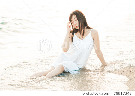 One-piece woman sitting on the beach 78917345