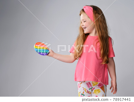 Happy smiling kid girl in pink clothes holds and Happy smiling kid girl in pink clothes holds and 78917441